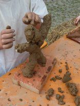 Aus Lehm geformte Figur auf einem Ziegelstein