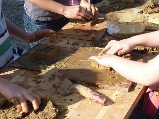 Kinder formen Lehmziegel auf einem Holztisch