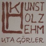 Sgraffito-Logo „Kunst Holz Lehm“ in rotbraunem Lehmputz